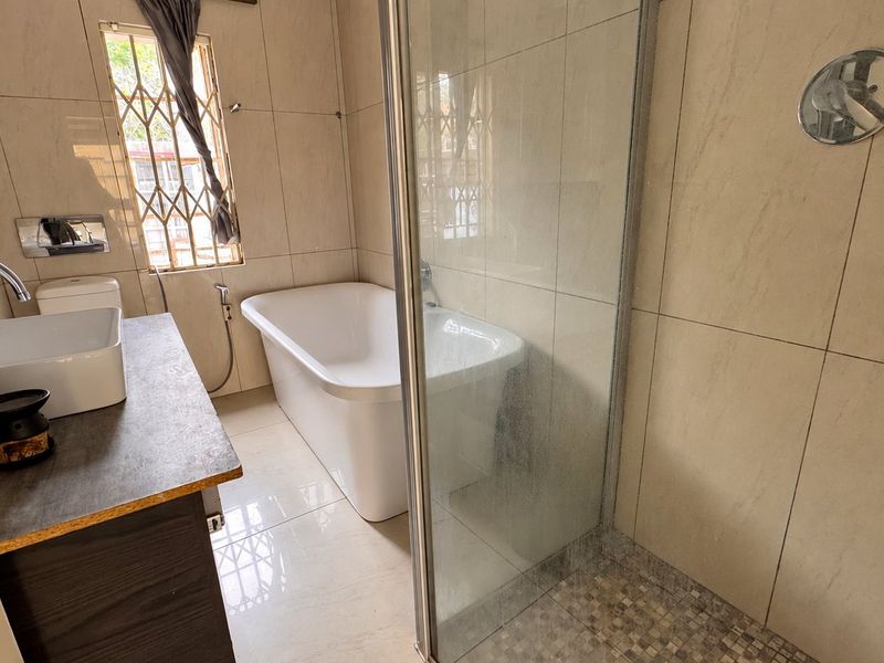 Modern bathroom featuring a freestanding bathtub, separate glass-enclosed shower, and a vessel sink vanity with tiled finishes throughout.