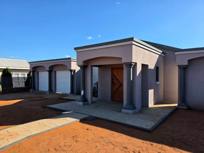 Front elevation of a modern house featuring a covered entrance porch, decorative columns, and a double garage with paved access.