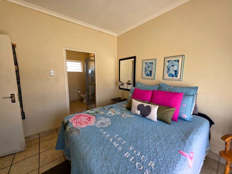 A bedroom featuring tiled flooring and direct access to an en-suite bathroom, with neutral wall finishes and coved ceiling detailing.