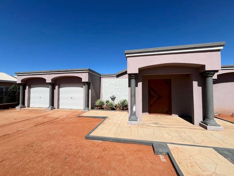 Front elevation of a house featuring a double garage, covered entrance with decorative columns, and a stone-clad feature wall.
