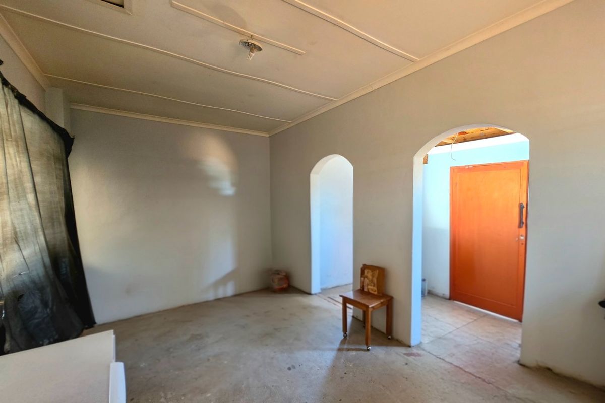 An empty living area featuring arched doorways, coved ceilings, and unfinished concrete flooring, offering a blank canvas for renovation and interior design.