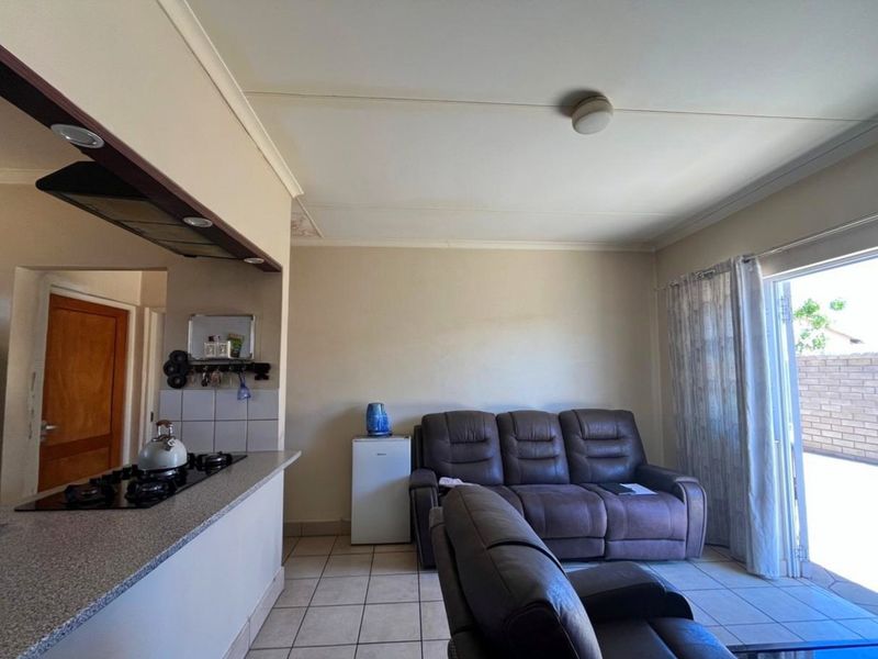 Open plan living area featuring a kitchen with a gas hob and tiled flooring, leading directly to an outdoor patio area.