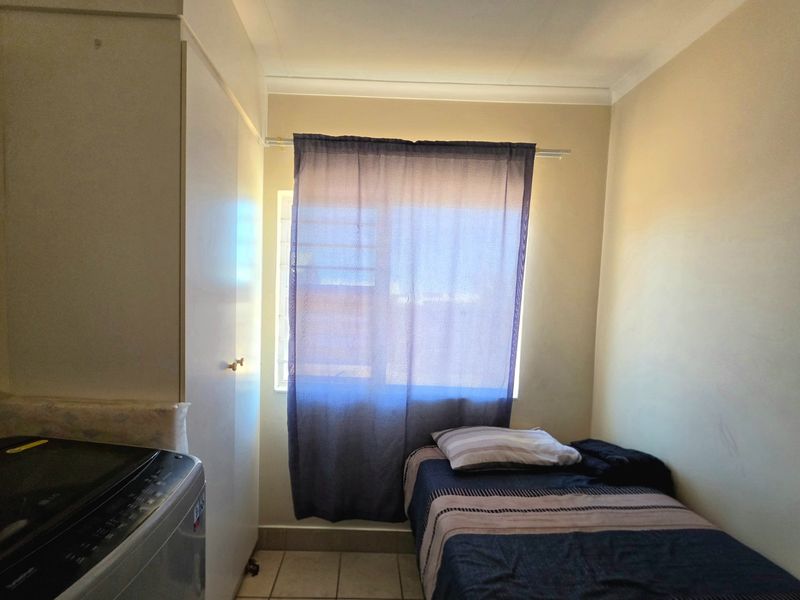 A compact bedroom featuring tiled flooring and a built-in cupboard, providing functional storage space.