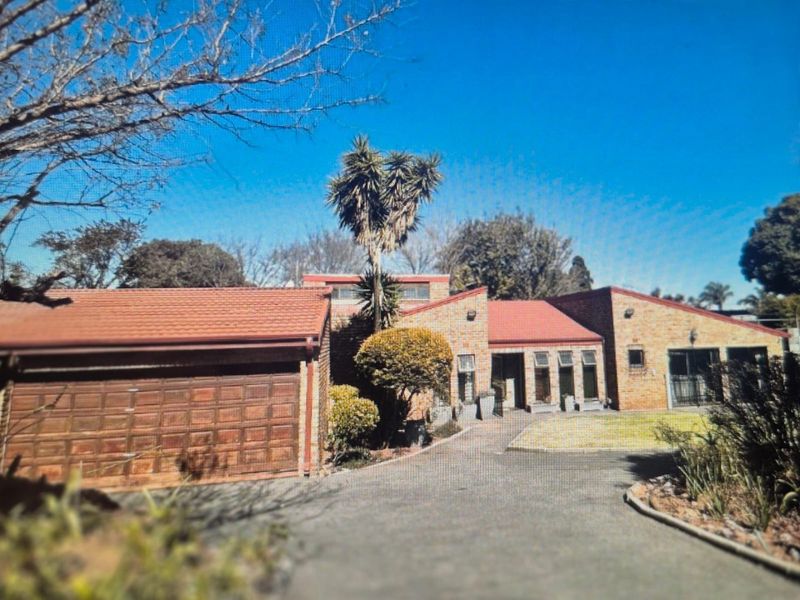 Front elevation of a face brick house featuring a tiled roof, double garage, and a paved driveway leading to the entrance.