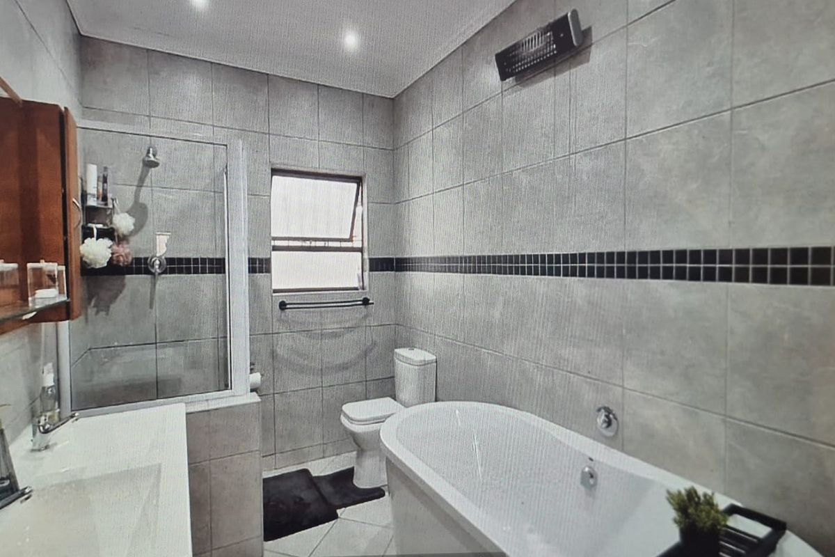 Modern bathroom featuring a freestanding bathtub, glass-enclosed shower, and neutral tiled finishes throughout.