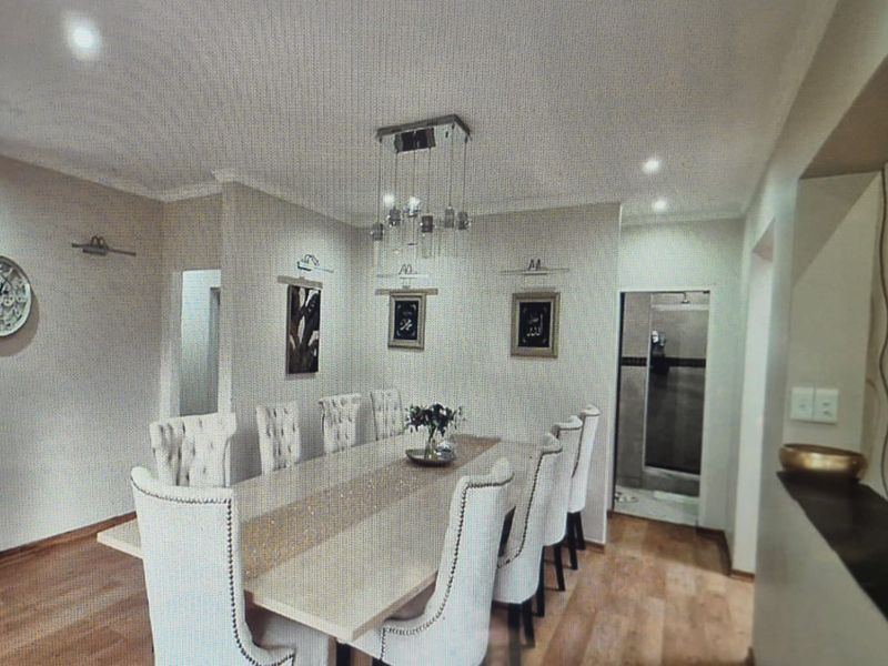 A well-lit dining area featuring modern recessed downlights, a contemporary pendant light fixture, and durable laminate flooring.