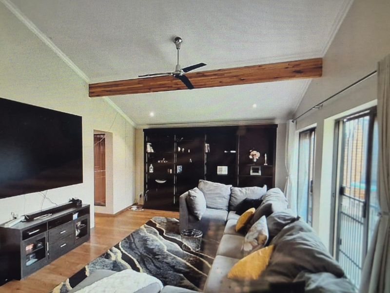 Spacious living room featuring an exposed timber ceiling beam, built-in shelving, and large sliding glass doors that provide ample natural light.