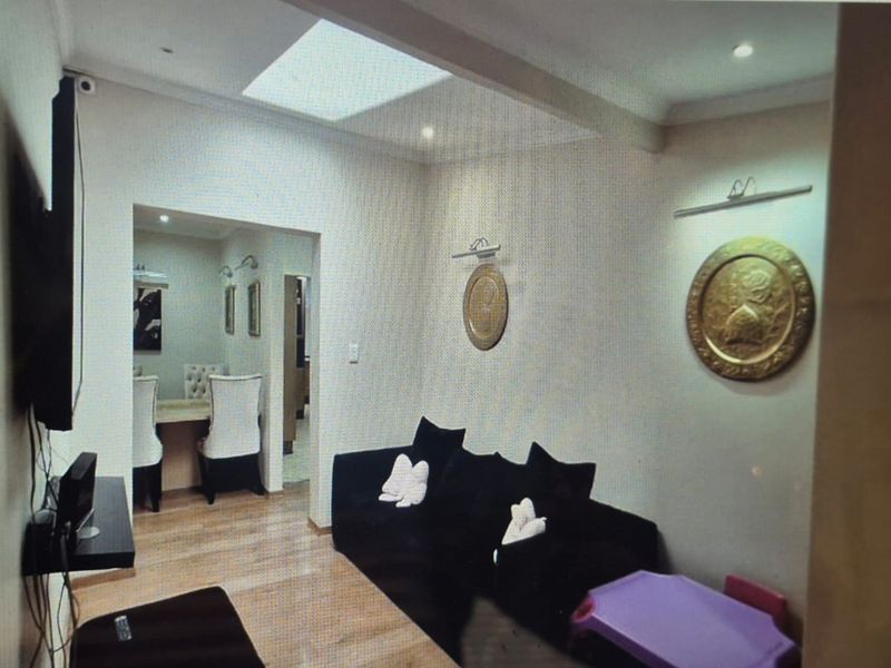 A living room featuring laminate flooring, a skylight providing natural light, and recessed ceiling lighting.