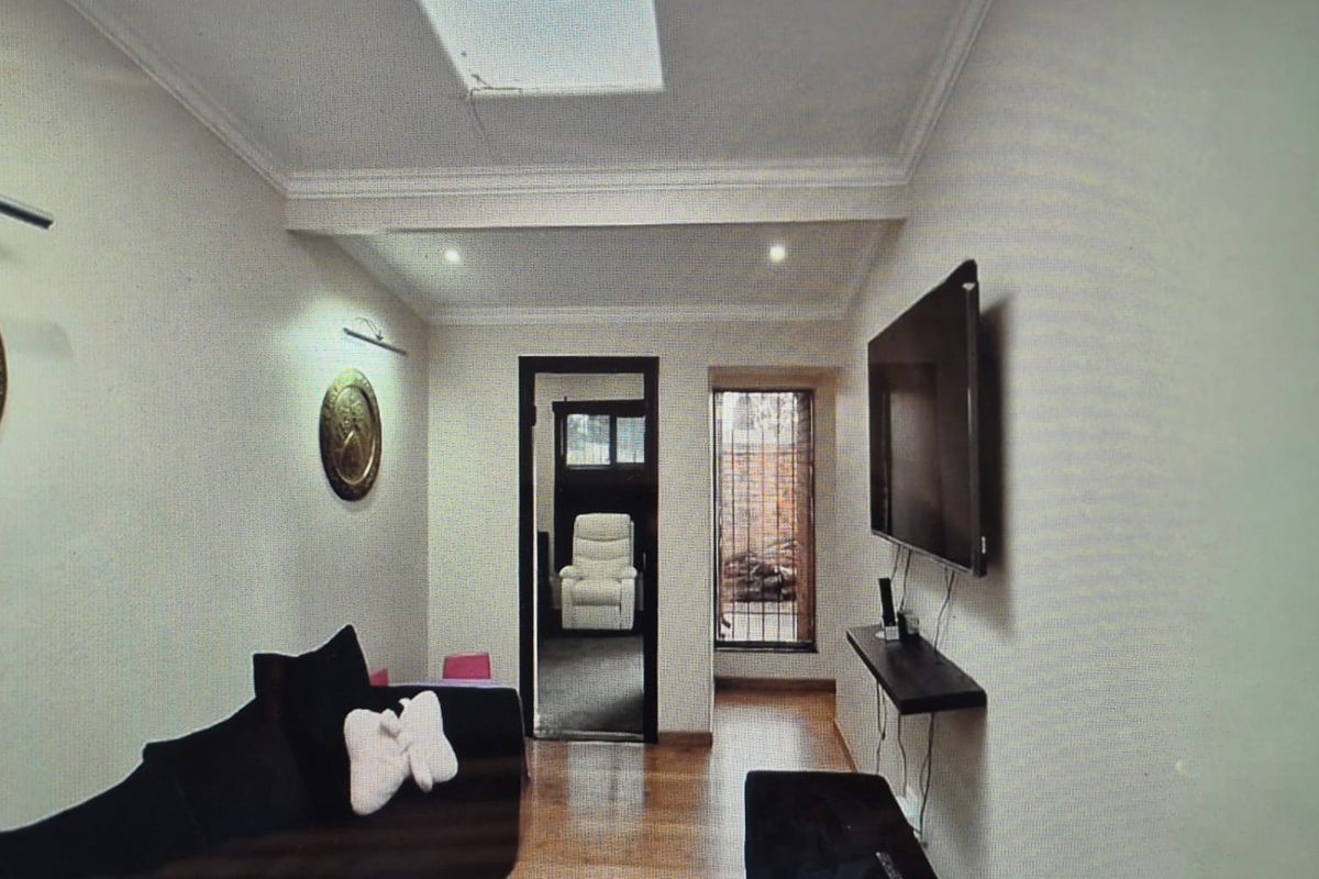 A living room featuring hardwood flooring, recessed lighting, and a skylight, with security bars on the window.