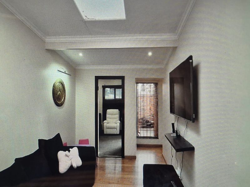 A living room featuring hardwood flooring, recessed lighting, and a skylight, with security bars on the window.