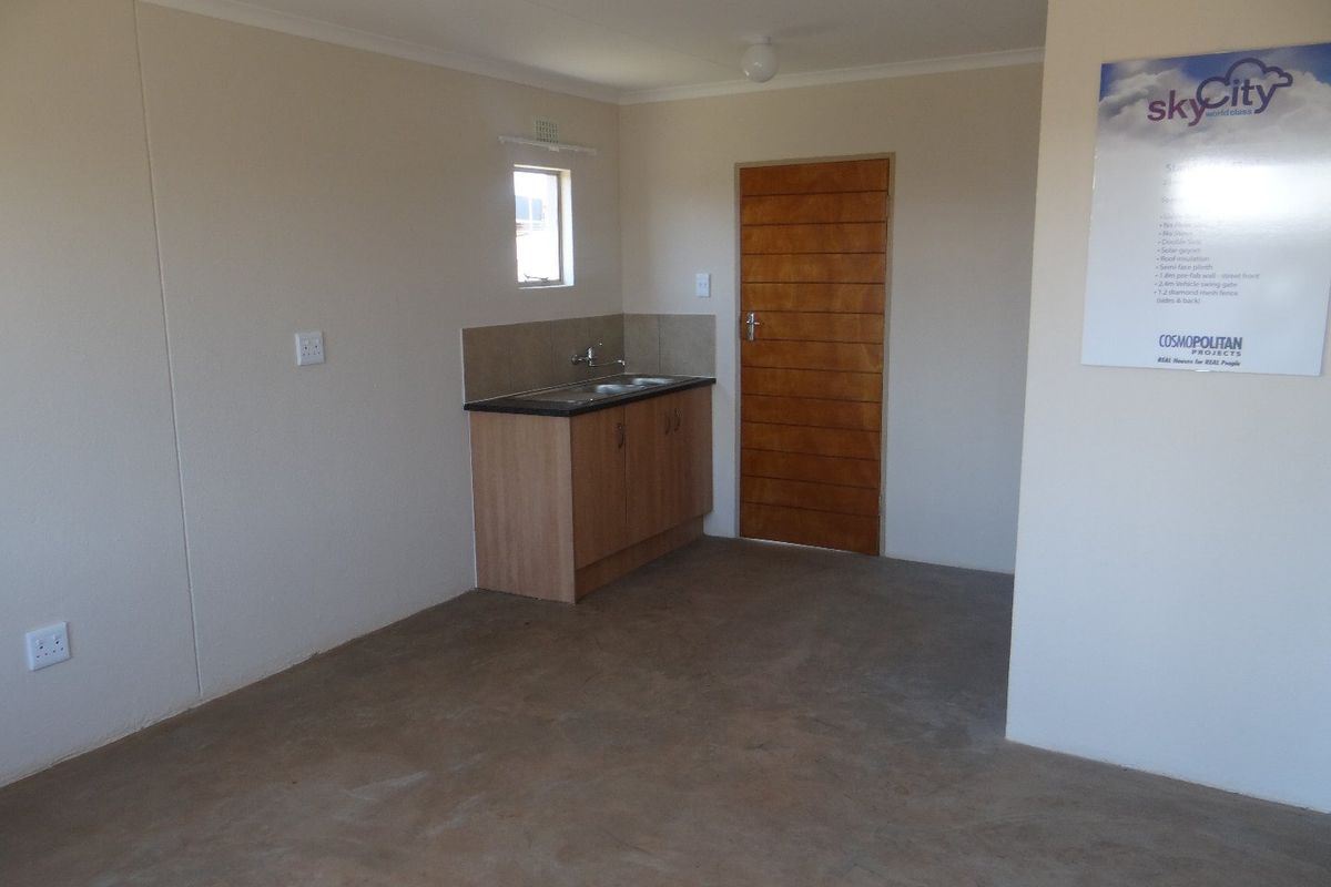 A compact, empty kitchen area featuring basic base cabinetry, a sink, and tiled splashback, suitable for a starter home or utility space.