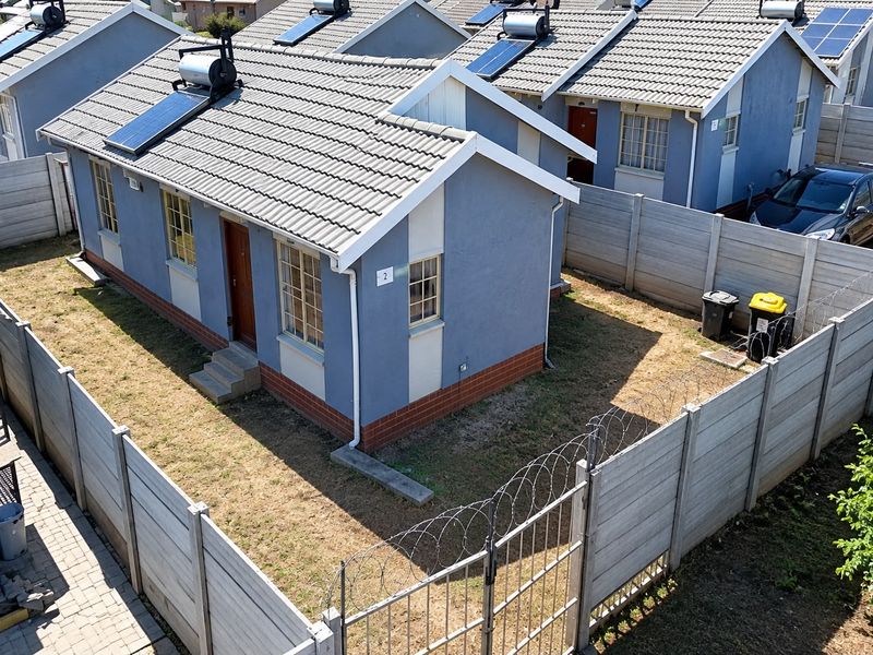 Aerial view of a residential property featuring a tiled roof with solar water heating, enclosed by precast concrete walls with security razor wire.