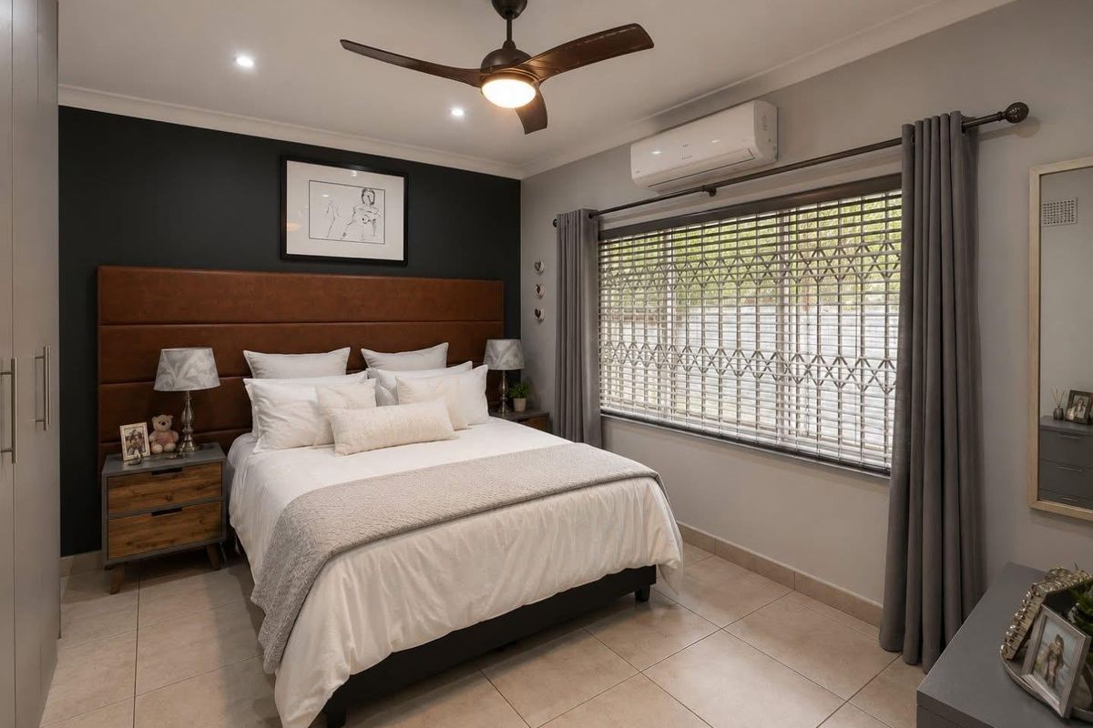 A well-maintained bedroom featuring tiled flooring, a ceiling fan, split system air conditioning, and built-in wardrobe storage.