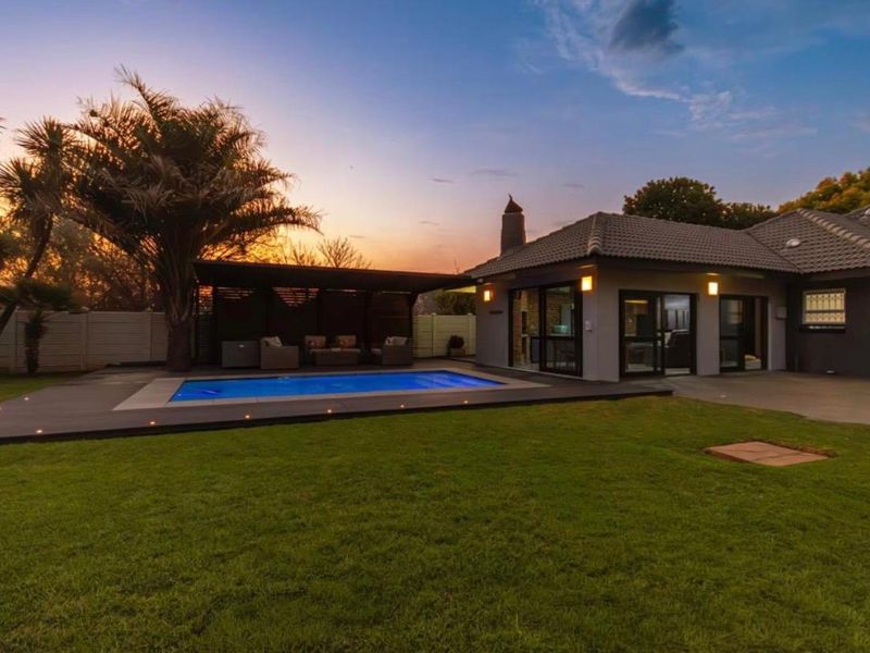 A beautifully landscaped rear garden featuring a swimming pool, modern decking, and a covered patio area, perfect for outdoor entertaining.