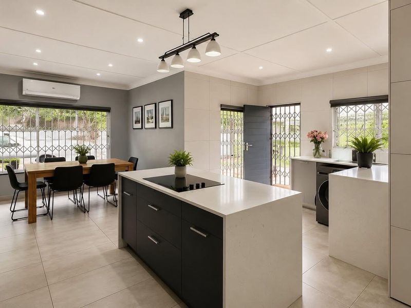 Modern open-plan kitchen and dining area featuring a central island, sleek cabinetry, built-in appliances, and neutral tiled flooring with ample natural light.