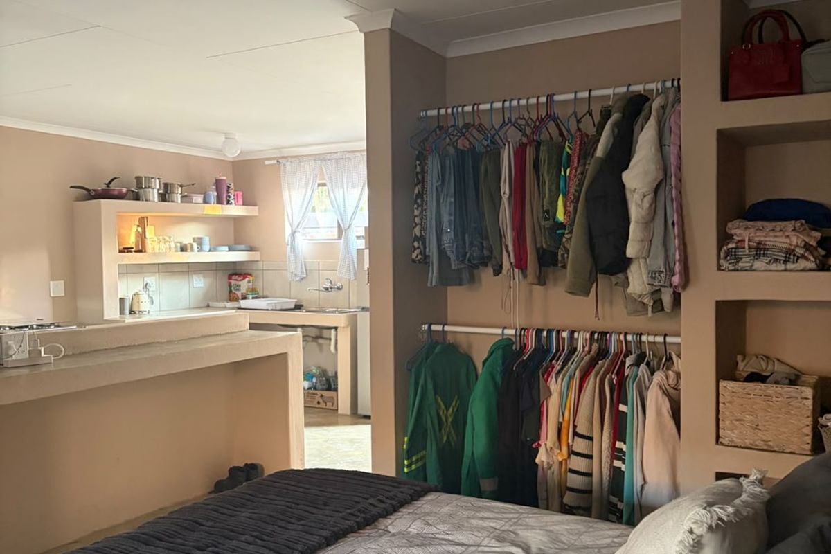 Open plan studio apartment featuring a combined bedroom and kitchen area with built-in shelving and a functional kitchen counter.