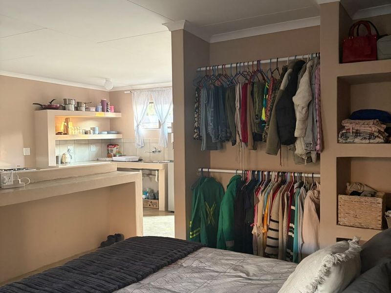 Open plan studio apartment featuring a combined bedroom and kitchen area with built-in shelving and a functional kitchen counter.
