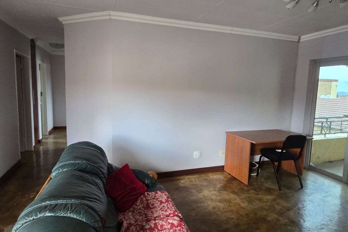 A living room area featuring a sliding glass door leading to a balcony, air conditioning unit, and neutral wall finishes.