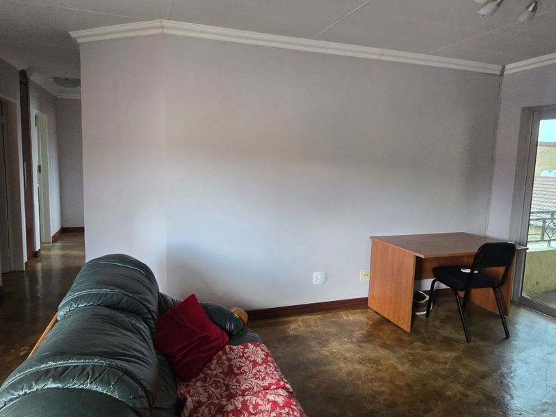 A living room area featuring a sliding glass door leading to a balcony, air conditioning unit, and neutral wall finishes.