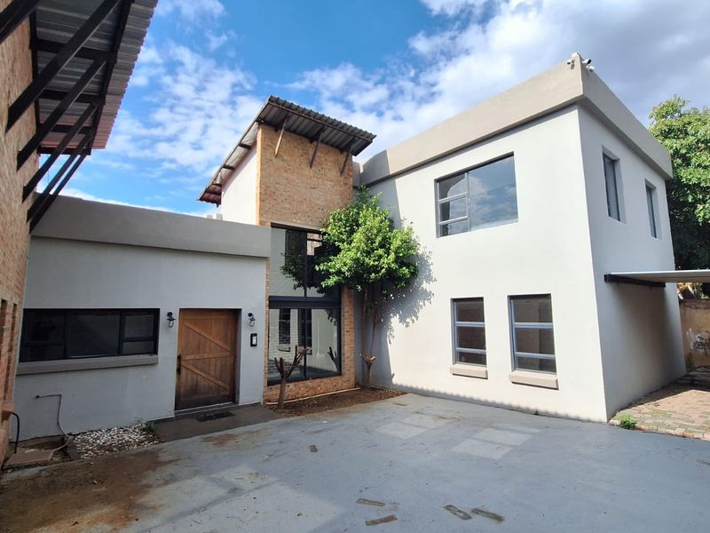 Front exterior view of a modern double-storey house featuring a mix of exposed brick and plastered finishes with a timber entrance door.