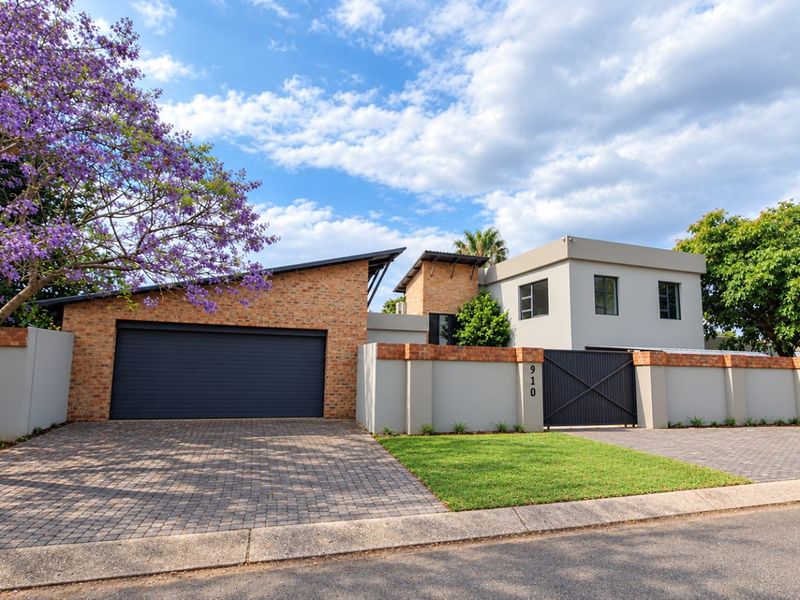 Modern double-story house featuring a brick and rendered facade, paved driveway, secure boundary wall, and an automated double garage.