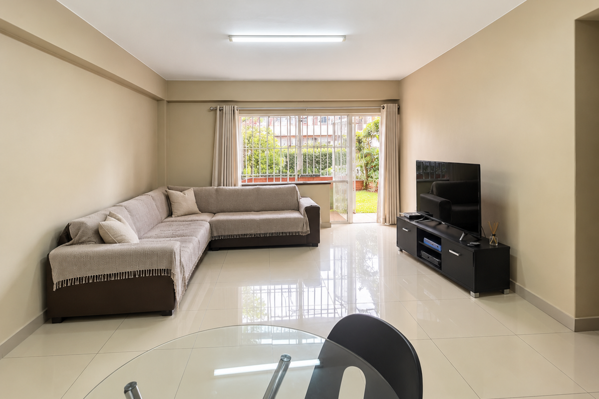 A spacious living room featuring neutral walls, polished tiled flooring, and a sliding glass door providing access to an outdoor area.