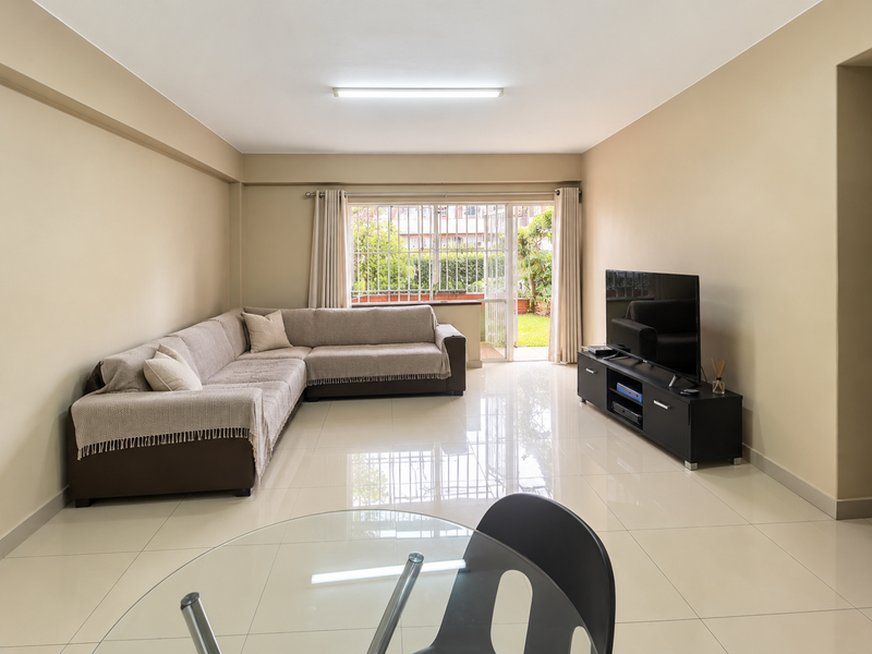 A spacious living room featuring neutral walls, polished tiled flooring, and a sliding glass door providing access to an outdoor area.