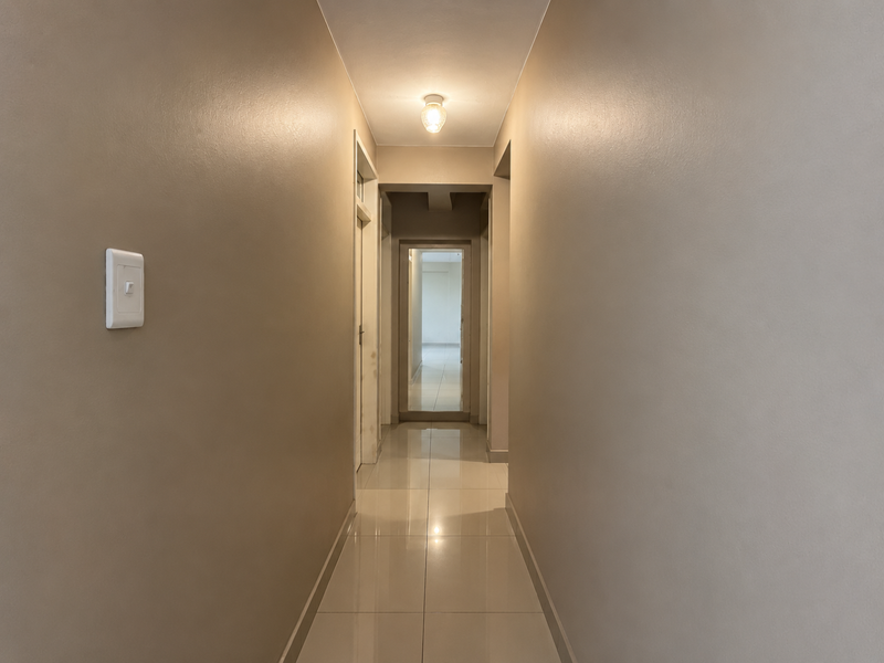 A clean, well-lit hallway featuring neutral-toned walls and polished tile flooring, providing a seamless transition between rooms in the apartment.