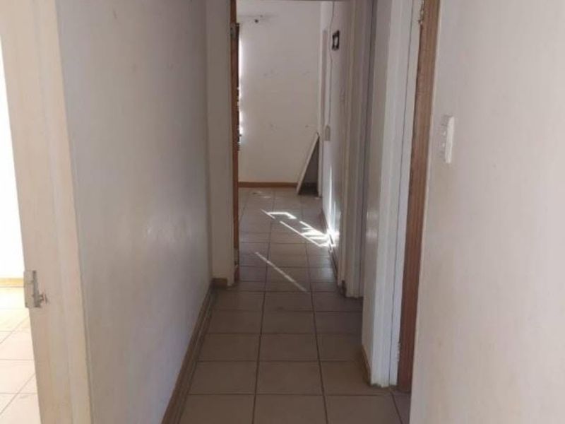A vacant hallway featuring tiled flooring and neutral walls, providing access to multiple rooms within the apartment.