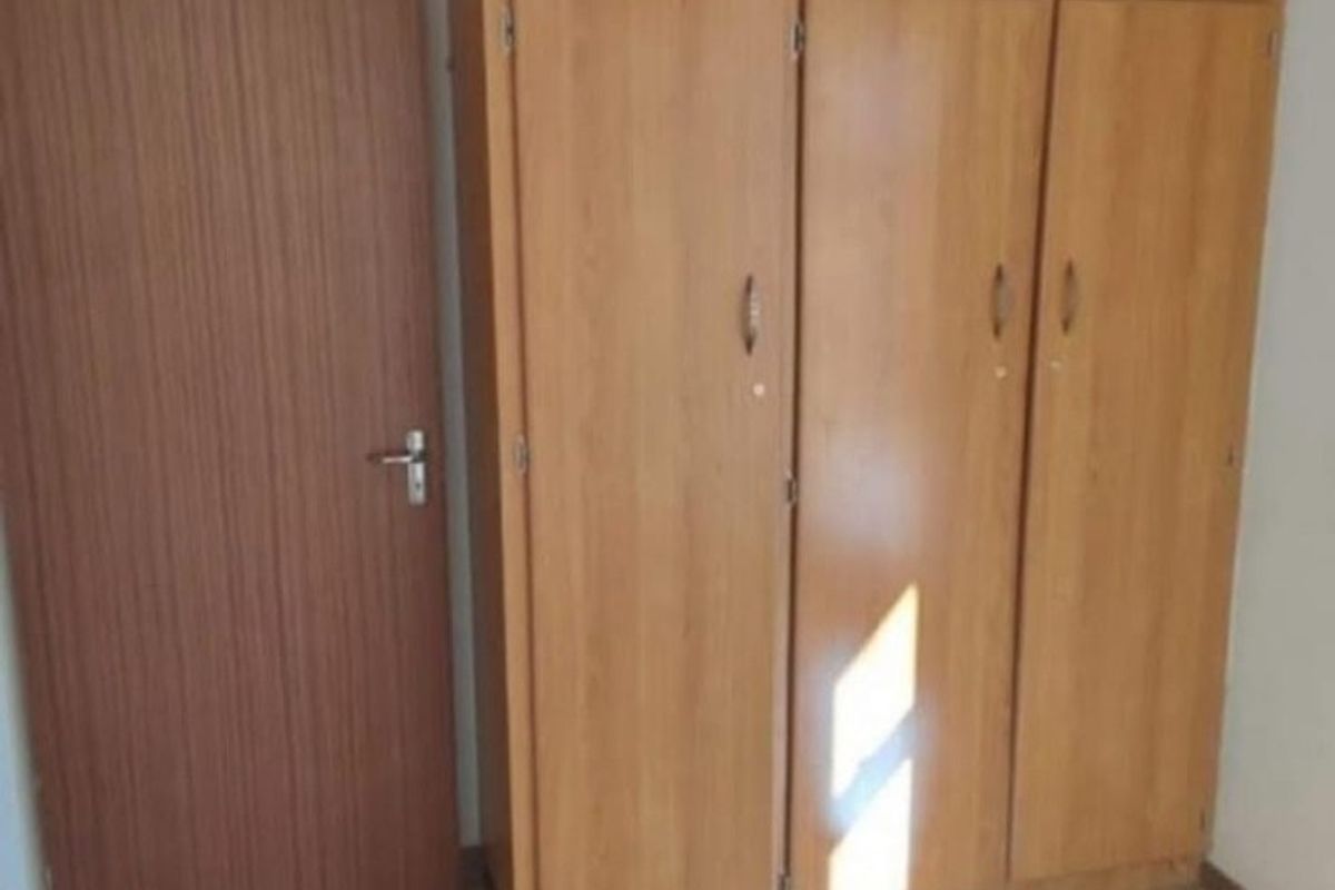 A bedroom featuring built-in wooden cupboards and tiled flooring, offering a clean and functional space ready for personalization.