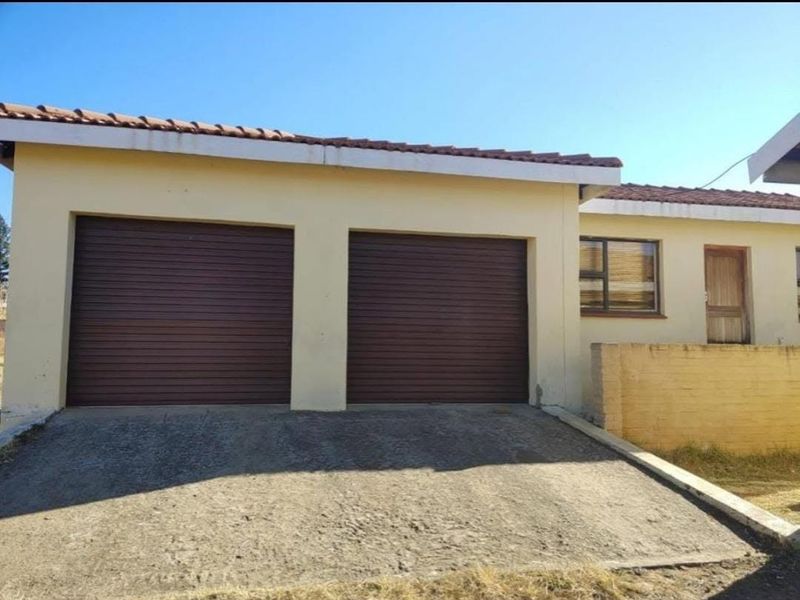 Exterior view of a double garage featuring roll-up doors, a concrete driveway, and a tiled roof, set against a residential building facade.