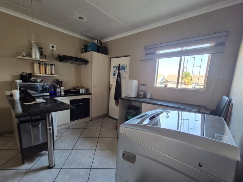 Functional kitchen featuring built-in oven, extractor fan, granite countertops, and tiled flooring, with a window providing natural light and security bars.