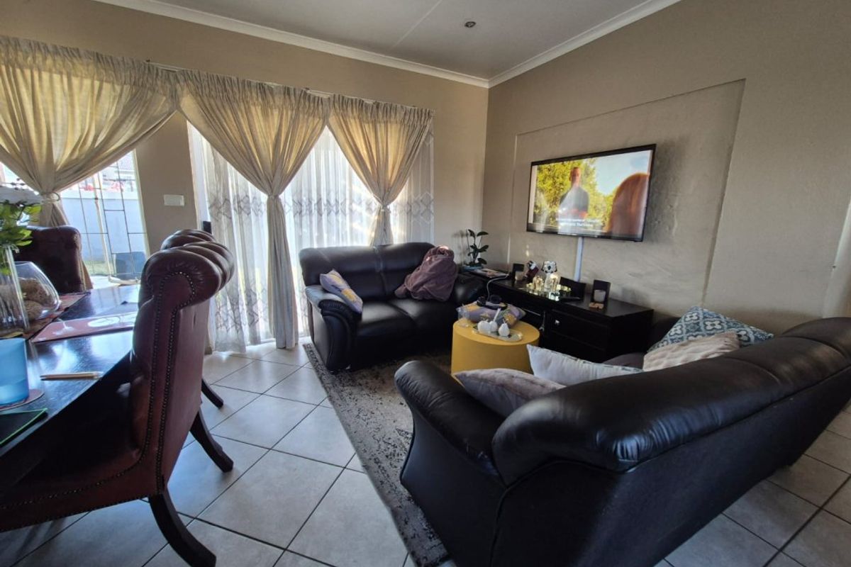 A comfortable living area featuring tiled flooring, a recessed wall section for media, and large sliding glass doors providing natural light.
