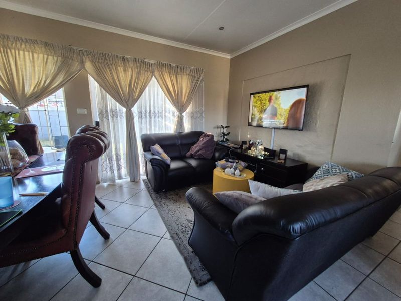 A comfortable living area featuring tiled flooring, a recessed wall section for media, and large sliding glass doors providing natural light.