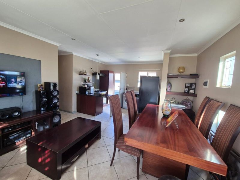 Spacious open-plan living and dining area featuring tiled floors, recessed lighting, and a functional kitchen with granite countertops and built-in cabinetry.
