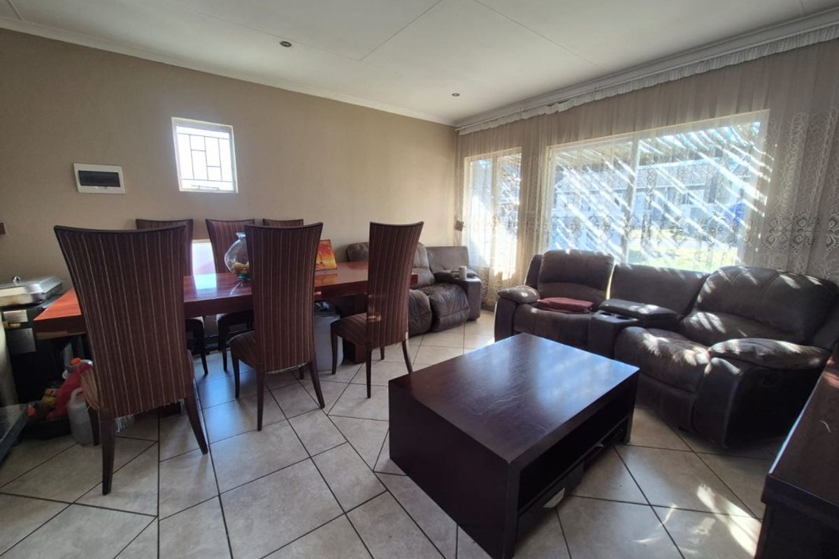 An open-plan living and dining area featuring tiled flooring, recessed ceiling lighting, and large windows allowing for natural light.