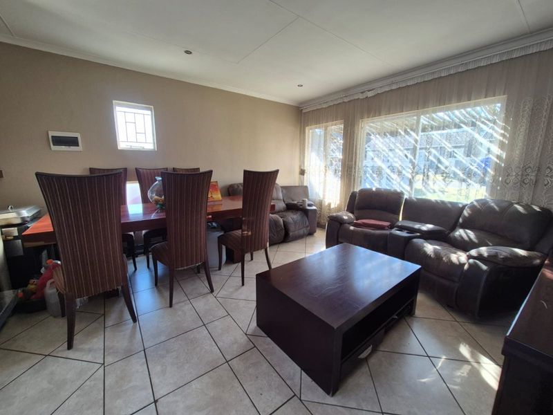 An open-plan living and dining area featuring tiled flooring, recessed ceiling lighting, and large windows allowing for natural light.