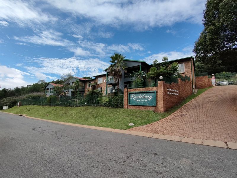 Front exterior view of the Roodeberg apartment complex featuring brick facade, paved driveway, and established landscaping.