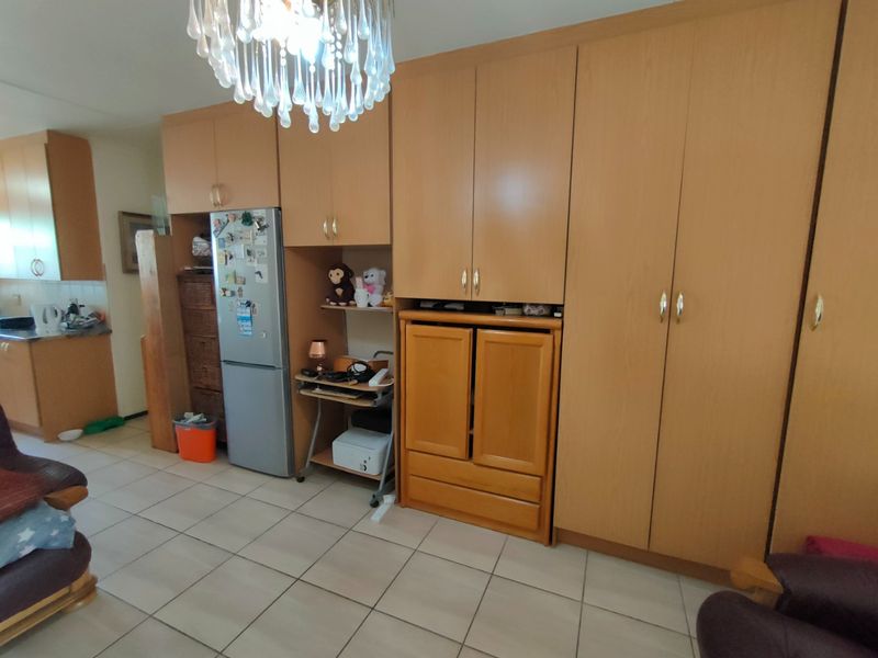 Open plan living area featuring extensive built-in wooden cabinetry and tiled flooring, with an adjacent kitchen area visible in the background.