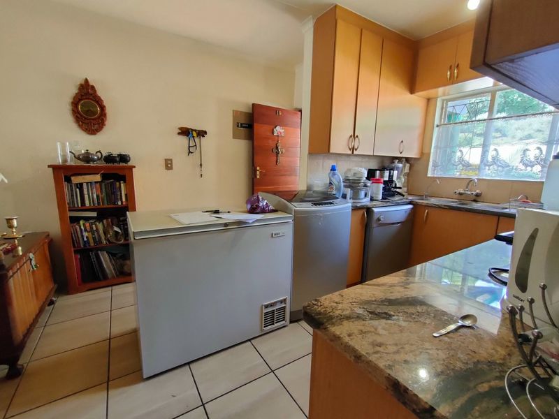 A functional kitchen featuring laminate cabinetry, granite countertops, and tiled flooring, offering a practical layout with integrated sink and ample storage space.