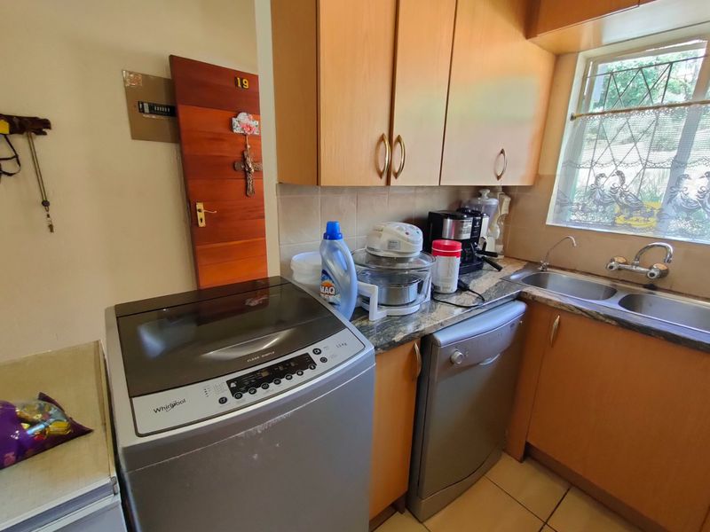 A functional kitchen area featuring laminate cabinetry, a double bowl stainless steel sink, and tiled splashbacks, providing practical utility space.