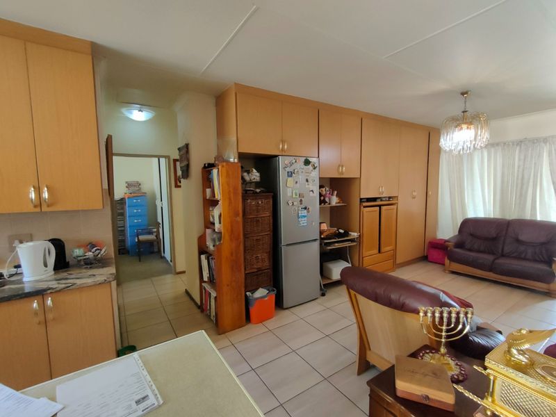 Open plan living area featuring tiled flooring and extensive built-in cabinetry, combining kitchen and lounge space in a functional layout.