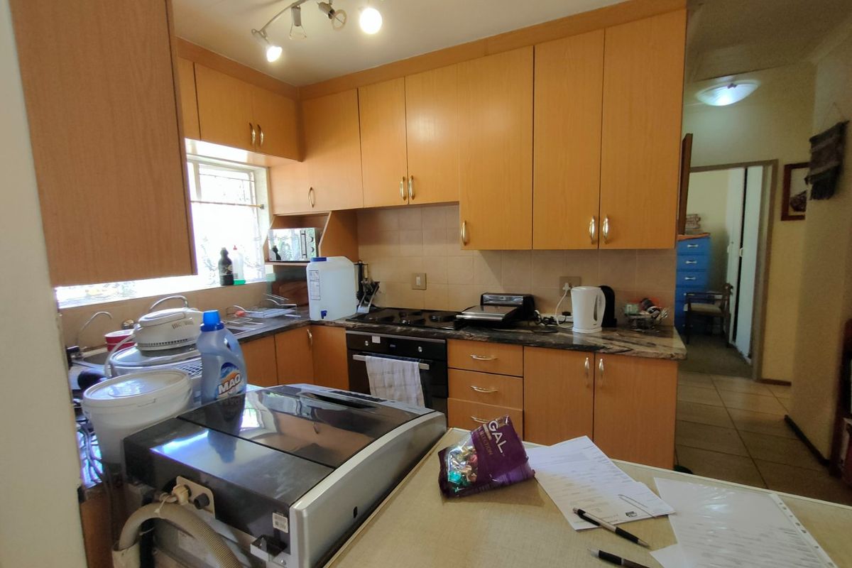 A functional kitchen featuring light wood-finish cabinetry, laminate countertops, a built-in oven, and an electric hob with a tiled backsplash.