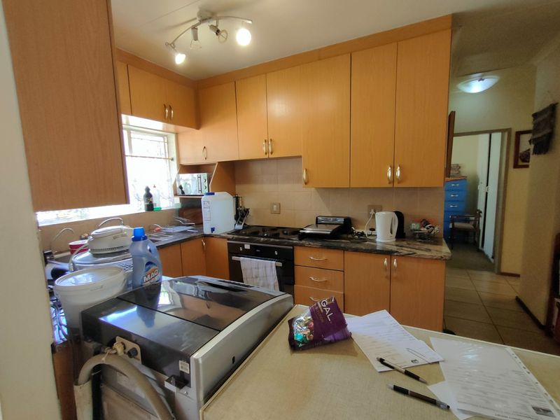 A functional kitchen featuring light wood-finish cabinetry, laminate countertops, a built-in oven, and an electric hob with a tiled backsplash.