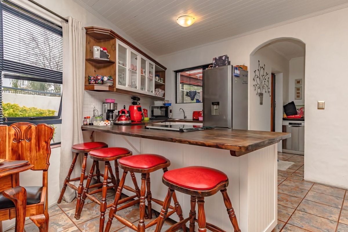 A functional kitchen featuring a wooden breakfast bar, tiled flooring, and classic cabinetry, providing a warm and practical cooking and dining space.