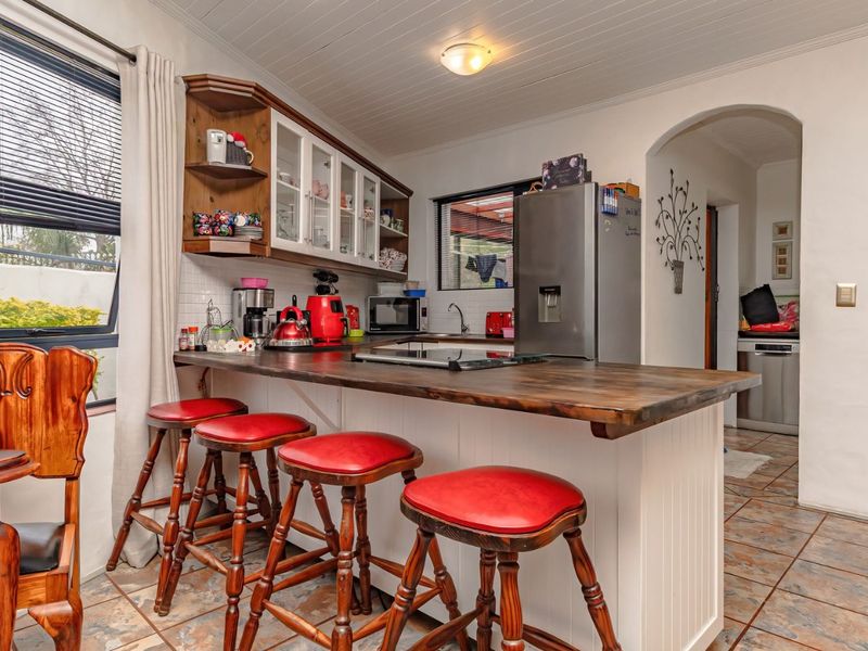 A functional kitchen featuring a wooden breakfast bar, tiled flooring, and classic cabinetry, providing a warm and practical cooking and dining space.