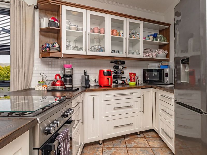A well-appointed kitchen featuring white cabinetry, wooden countertops, a subway tile backsplash, and a gas stove, offering a functional and classic aesthetic.