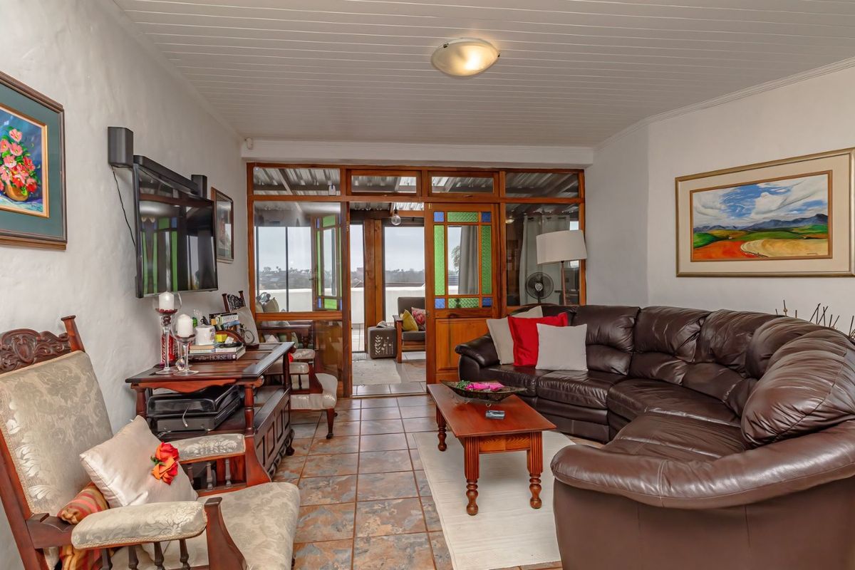 A comfortable living room featuring tiled flooring, a tongue and groove ceiling, and timber-framed glass doors leading to an outdoor patio area.
