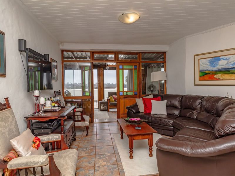 A comfortable living room featuring tiled flooring, a tongue and groove ceiling, and timber-framed glass doors leading to an outdoor patio area.
