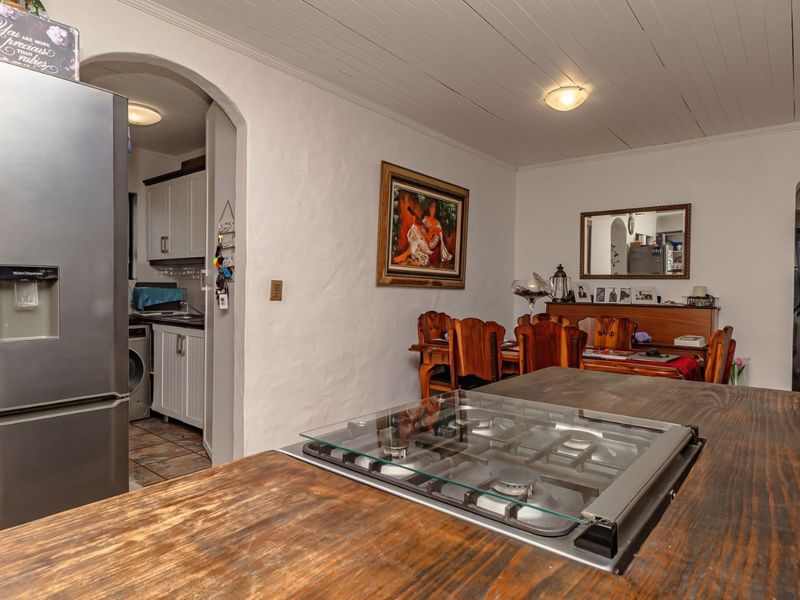 Open plan kitchen and dining area featuring a central island with a gas hob, wooden countertops, and classic archway transitions.